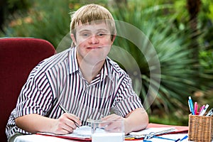 Boy with down syndrome at desk outdoors.