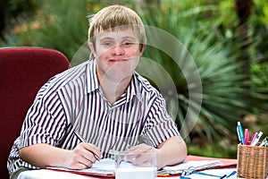 Boy with down syndrome at desk outdoors. photo
