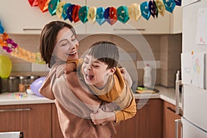 Boy with Down syndrome laughing out loud while his mother holding him