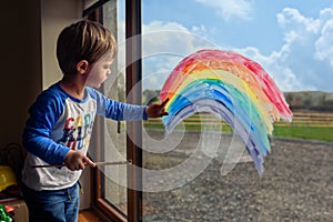 Boy drawing rainbow on the window