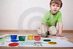 Boy draws color paints and makes handprints