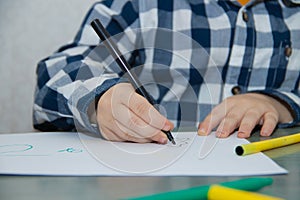 The boy draws felt-tip pens on paper. Drawing. Little boy. Children`s drawing. Developmental activities