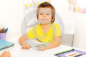 Boy draws with pen during sitting at table