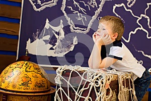 Boy dreams, sitting next to the globe. Future traveler