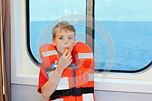 Boy dressed in life jacket blows whistle