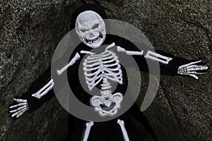 Boy dressed up as skeleton posing on rock