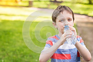 Boy drinking mineral water from the plastic bottle