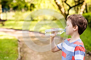 Boy drinking mineral water from the plastic bottle