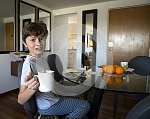 Boy drinking orange juice and eating eggs for breakfast