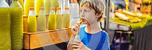 Boy drinking sugar cane juice on the Asian market BANNER, LONG FORMAT