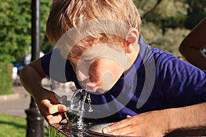 Boy drinks water from street tap on hot summer day. To quench his thirst. Close-up
