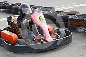 Boy is driving Go-kart car with speed in a playground racing track