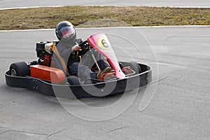 Boy is driving Go-kart car with speed in a playground racing track