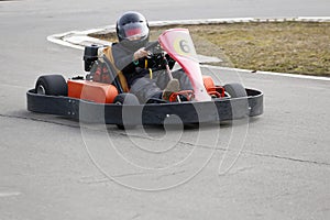 Boy is driving Go-kart car with speed in a playground racing track