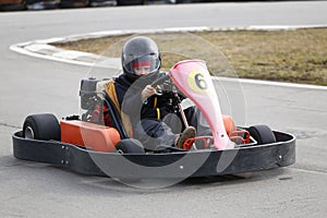 Boy is driving Go-kart car with speed in a playground racing track