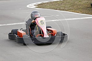 Boy is driving Go-kart car with speed in a playground racing track