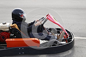 Boy is driving Go-kart car with speed in a playground racing track