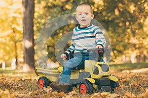 Boy driving a toy truck in park outdoors