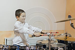 Boy drumming. boy in a white shirt plays the drums
