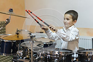 Boy drumming. boy in a white shirt plays the drums. A boy in a white shirt is drumming