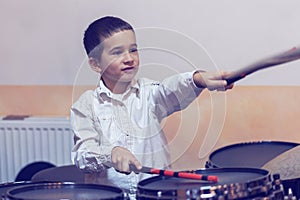 Boy drumming. boy in a white shirt plays the drums. A boy in a white shirt is drumming. toned