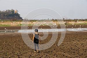 Boy in dryland looking at drought landscape. Concept for climate change from global worming.