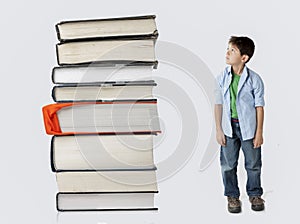 Boy dwarfed by stack of books.
