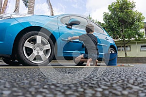 Boy earning pocket money cleaning blue compact car