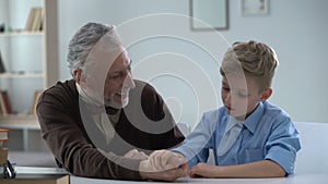 Boy easily defeating grandfather in arm wrestling happy with victory, family fun