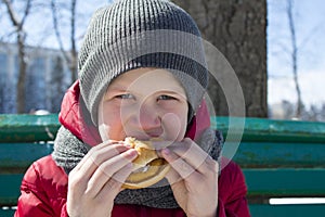 Boy is eating burger outdoor
