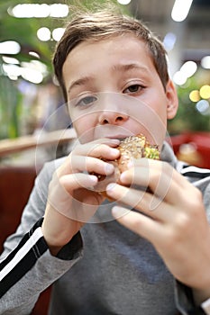 Boy eating burger in restaurant