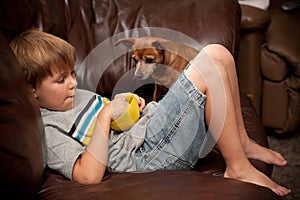 Boy eating cereal with little dog watching