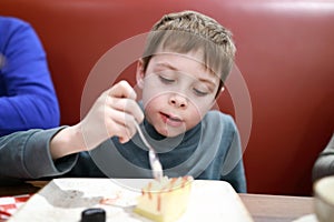 Boy eating cheesecake in restaurant