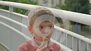 A boy eating ice cream in the city. Against the background of passing cars