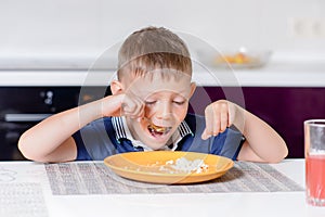 Boy Eating Last Bite of Food at Kitchen Table