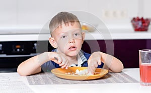 Boy Eating Last Bite of Food at Kitchen Table