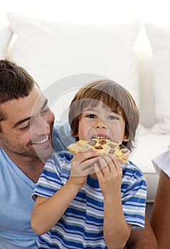 Boy eating pizza in living-room with his father