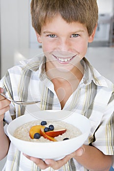 Boy eating porridge at home smiling