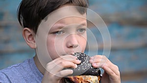 Boy eats a black burger