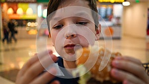 Boy eats a burger close up.