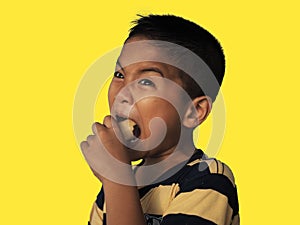 The boy eats hot dog solated on a yellow background. Embed clipping path. Junk food concept