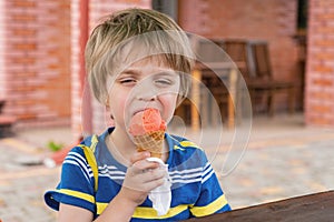 The boy eats ice cream. He narrowed his eyes in pleasure