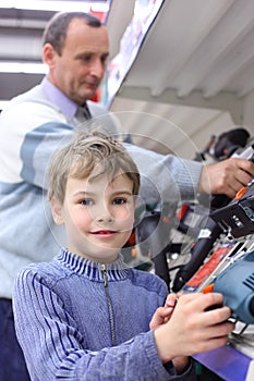 Boy with elderly man in shop of electrotools