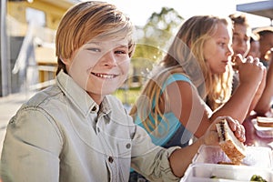 Boy at elementary school lunch table smiling to camera