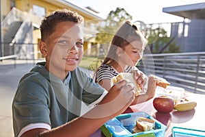 Boy at elementary school lunch table smiling to camera