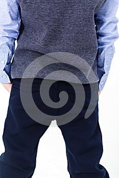 Boy, elementary school student posing in a school uniform on a white background. The boy stands with his back to the