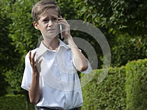 The boy emotionally speaks in the park by phone