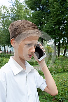 The boy emotionally speaks in the park by phone