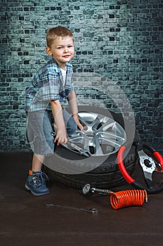 Boy is engaged in repair of wheels cars