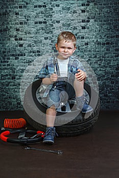Boy is engaged in repair of wheels cars